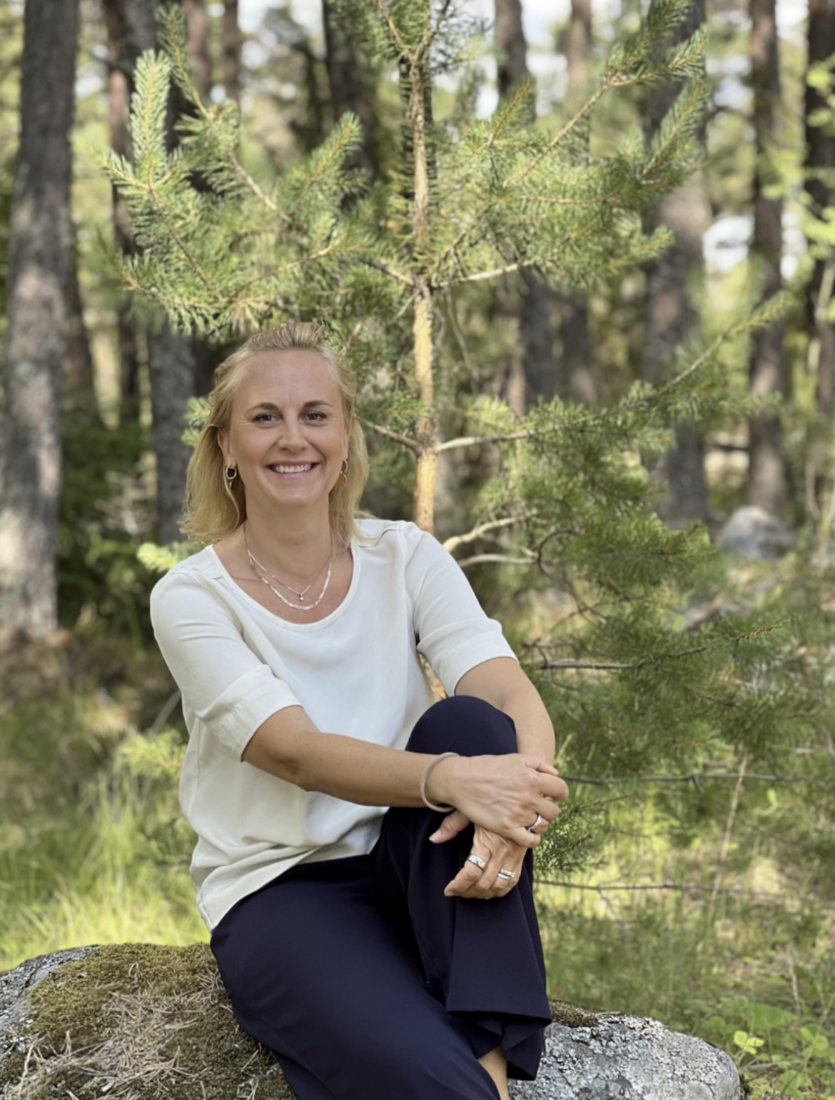 Carolina Ståhlsten sittande på en sten i skogen